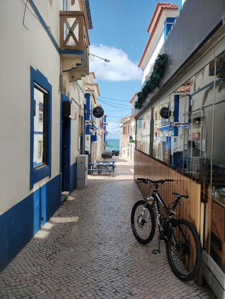 Uma rua estreita da Ericeira, de casas brancas com azul, a descer at&eacute; ao mar